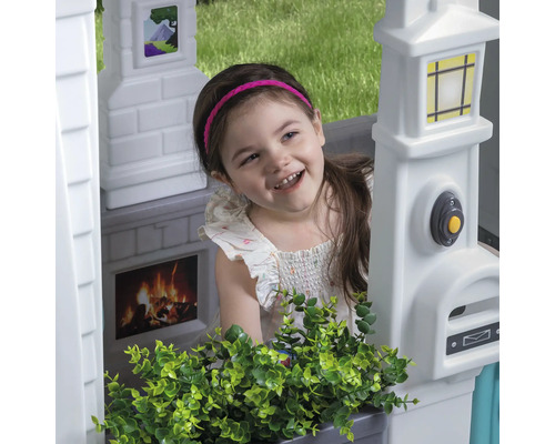 Fille dans une cabane de jeu avec boîte aux lettres, sonnette, cheminée et décoration de fenêtre