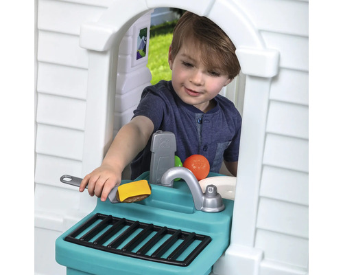 Garçon jouant avec une cuisine d''extérieur avec évier, barbecue et aliments jouets