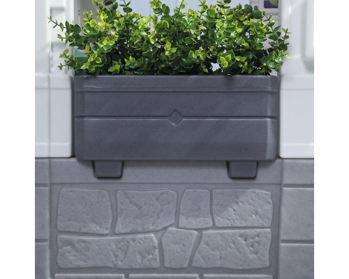 Jardinière grise avec plantes vertes sur un mur