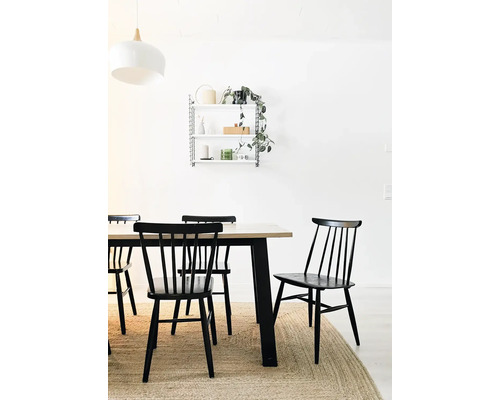 Salle à manger avec table en bois, chaises noires et étagère murale
