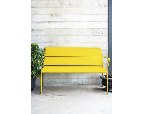 Banc en métal jaune à l''extérieur devant un mur en béton
