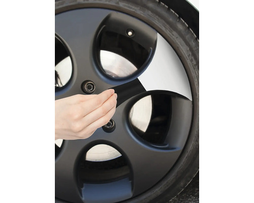 Person beklebt ein Autorad mit Klebeband