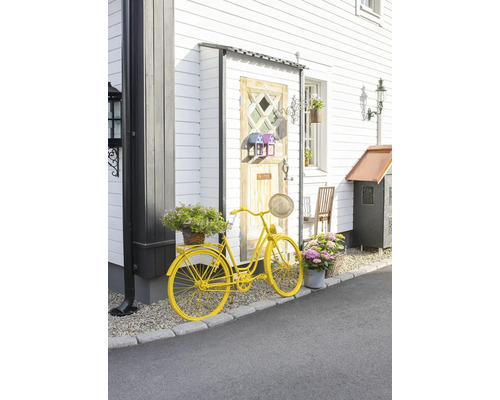 Vélo jaune décoratif avec des fleurs devant une maison.