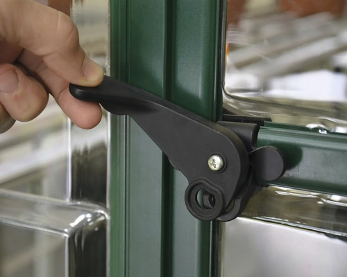 Gros plan d''une fenêtre de serre avec une poignée de fenêtre noire actionnée par une main