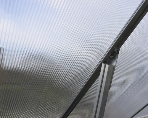 Gros plan sur une structure de serre avec plaques alvéolaires et cadre en aluminium