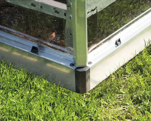 Detailansicht eines Gewächshauses aus Metall auf Gras.