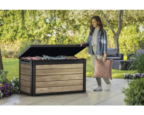Coffre de jardin ouvert en bois et métal avec une femme tenant un coussin