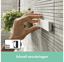 Eine Hand befestigt einen weißen Haken an einer Wandhalterung im Badezimmer.