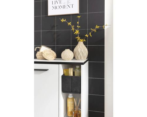 Scène de salle de bains avec meuble sous-lavabo, décoration et articles de bain devant un mur carrelé