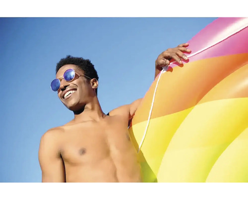 Homme avec des lunettes de soleil et une bouée gonflable devant un ciel bleu