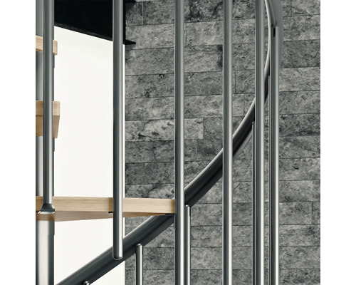 Vue détaillée d''un escalier en colimaçon avec garde-corps en métal et marches en bois devant un mur en pierre.