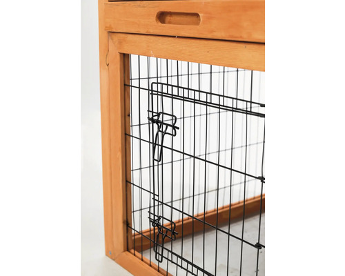 Detailansicht eines Kleintierstalls mit Gittertür und Holzrahmen.