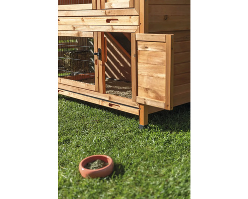 Vue détaillée d''un clapier en bois avec une porte ouverte et une gamelle sur la pelouse