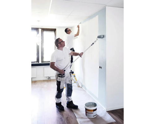 Zwei Handwerker streichen einen Raum mit Farbroller und Pinsel