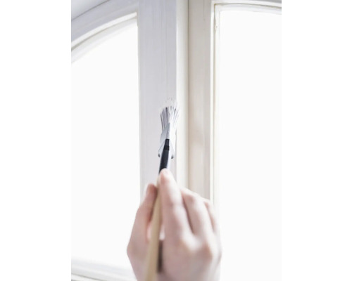 Main peignant un cadre de fenêtre avec un pinceau et de la peinture