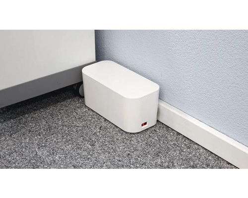 Image d''un boîtier de câbles rectangulaire blanc sur le sol à côté d''un mur