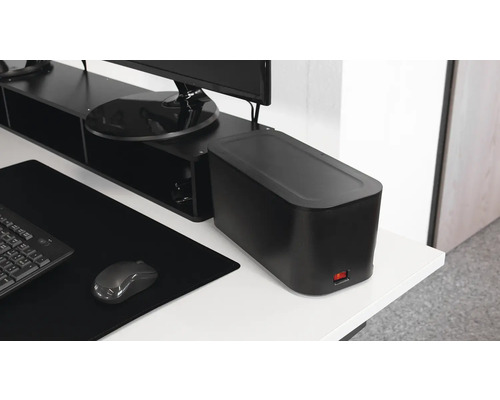 Schreibtisch mit schwarzer Kabelbox, Tastatur, Maus und Monitorständer