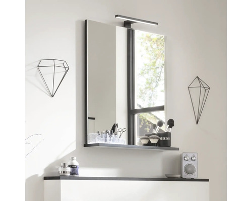 Miroir de salle de bain avec étagère et lampe, complété par des décorations géométriques pour un look moderne