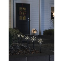 Dekorative Gartenbeleuchtung mit Sternmotiven vor einem Haus mit Türkranz