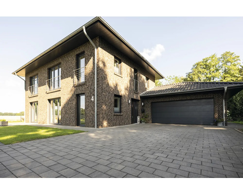 Une maison en briques à deux étages avec garage et allée pavée