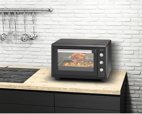 Mini-four sur un comptoir de cuisine avec poulet rôti et légumes à l''intérieur.