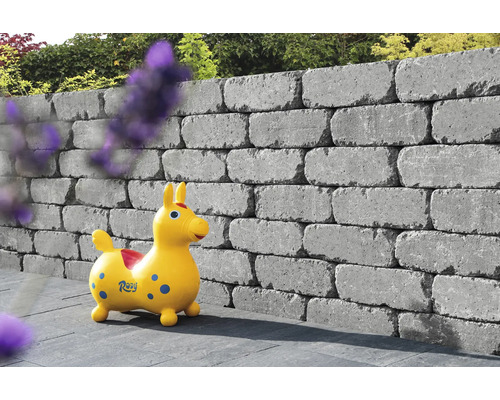 Des pierres de mur empilées forment un mur de jardin avec un cheval jouet devant.