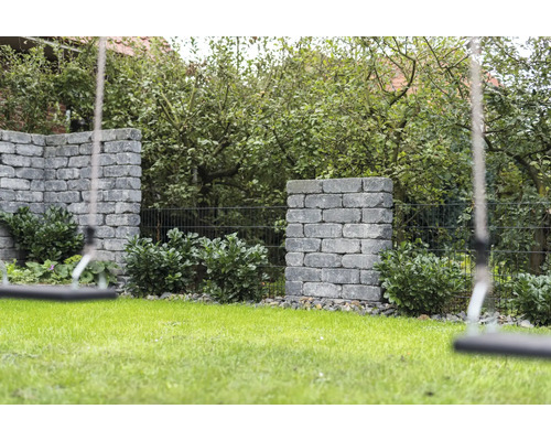 Garten mit Rasenfläche, bepflanzten Steinmauern und Schaukel