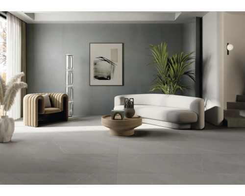 Salon lumineux avec fauteuil, canapé, table et sol carrelé.