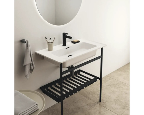 Lavabo avec structure noire, rangement et miroir rond dans la salle de bain.
