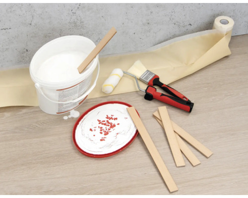 Farbeimer, Rührstäbe, Farbroller, Pinsel und Abdeckband auf dem Boden