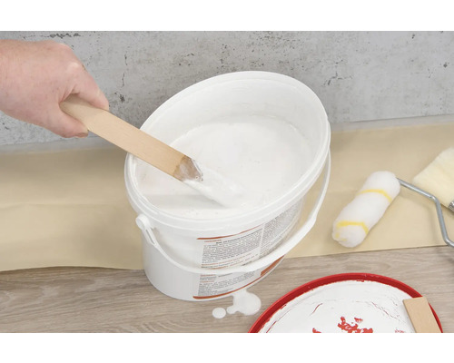 Farbeimer mit Holzrührer und Farbroller