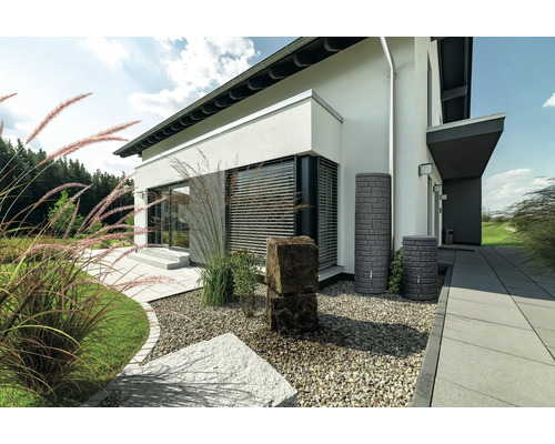 Gartenszene mit Regenwassertanks in Steinoptik neben einem modernen Haus