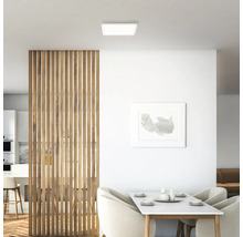Helle Inneneinrichtung mit quadratischer Deckenleuchte, Holztrennwand und Esstisch.