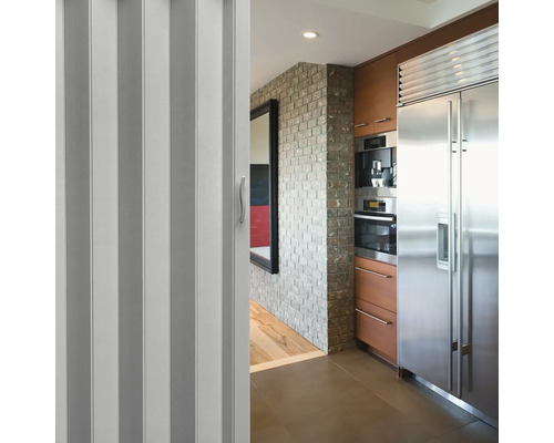 Porte pliante dans un espace cuisine avec des appareils en acier inoxydable et un mur en briques