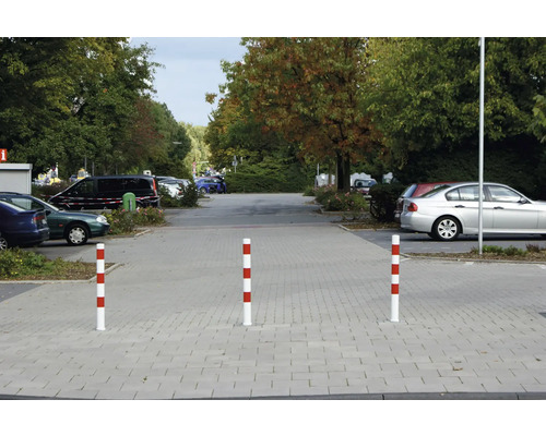 Drei rot-weiss gestreifte Absperrpfosten auf einem Parkplatz