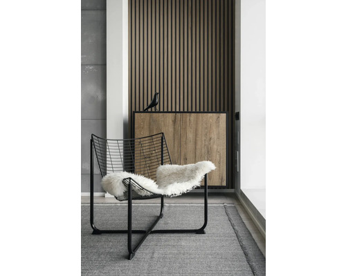 Intérieur avec fauteuil en fil de fer et mur en lambris