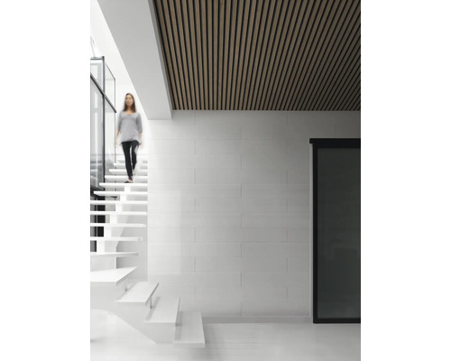 Pièce lumineuse avec plafond en bois, escalier et une personne.