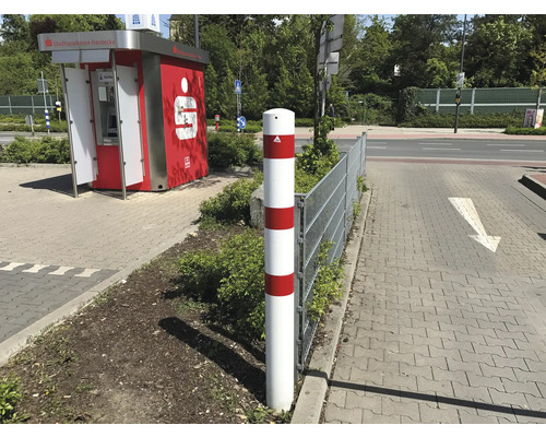Borne de délimitation blanche avec des bandes rouges à côté d''un trottoir