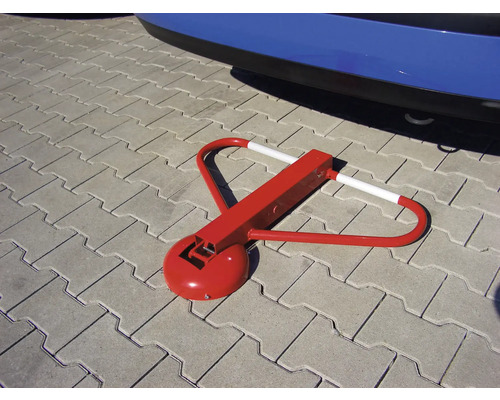 Barrière de stationnement rouge sur pavés devant une voiture