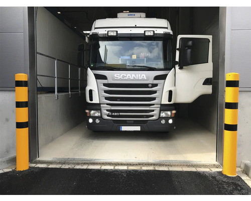 Ein Lastwagen fährt in ein Lagerhaus, flankiert von Anfahrschutzpfosten.