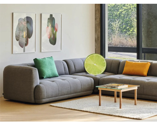 Graues Ecksofa mit Kissen, Couchtisch und gerahmten Kunstwerken im hellen Wohnzimmer