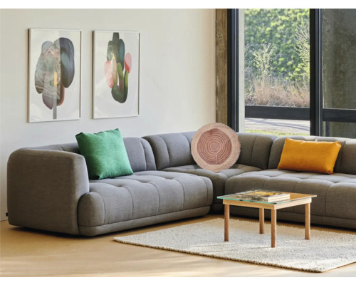 Wohnzimmer mit grauem Ecksofa, Zierkissen, Couchtisch und Kunst an der Wand