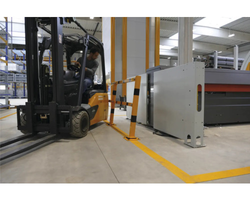 Chariot élévateur circulant dans un hall industriel, longeant une barrière