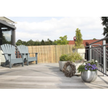 Terrassenszene mit zwei Holzstühlen, Bambuszaun und Pflanzgefäßen