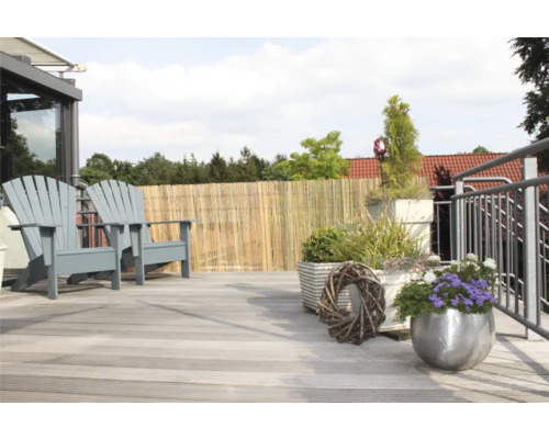 Terrassenszene mit zwei Holzstühlen, Bambuszaun und Pflanzgefäßen