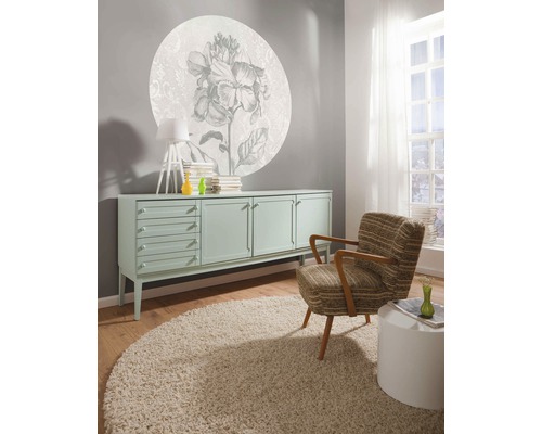 Salon avec commode, fauteuil, tapis et décoration murale à motifs floraux