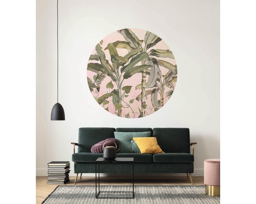 Salon avec canapé vert, tapis et décoration murale avec motif végétal