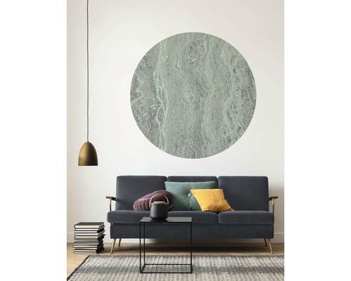 Salon avec canapé, table basse, théière, coussins, lampe, pile de livres, tapis et décoration murale