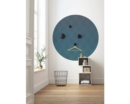 Hell eingerichteter Raum mit einem runden Wandbild, Haken, Kleiderbügel, Drahtkorb und Regal