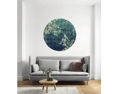 Wohnzimmer mit runder Wanddekoration mit Vogelmotiv über einem grauen Sofa.